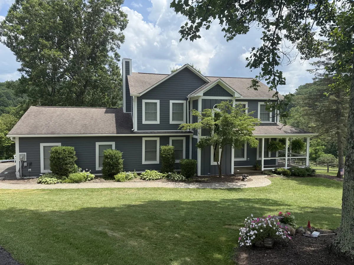 The same home after a full residing in slate blue lap and board-and-batten siding with white trim
