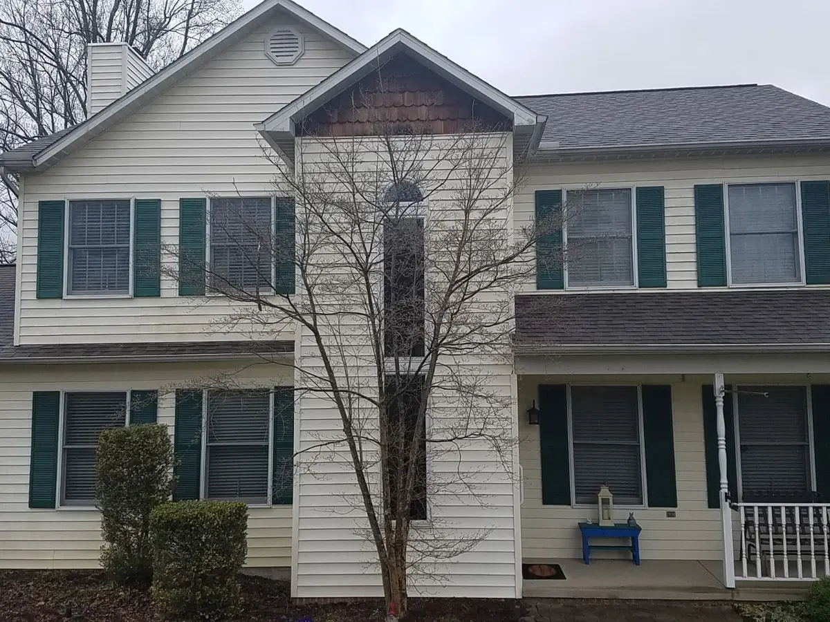 Two-story home with faded yellow vinyl siding before its remodel
