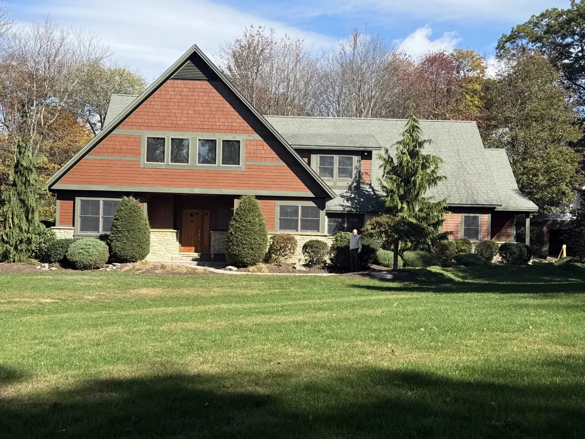 The same home after residing in rust-red shingle siding with sage green trim