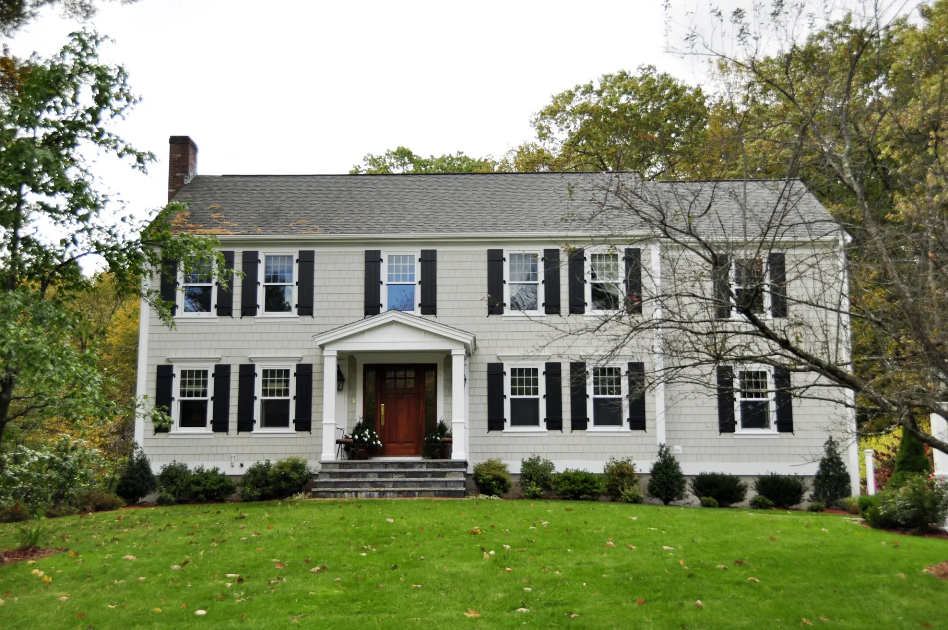 Classic colonial home with light gray James Hardie fiber cement shingle siding and black shutters